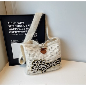 Detail of cream knit tote bag with leopard print letter patch and horn button closure