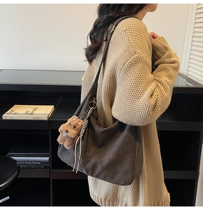 Grande borsa tote in pelle marrone con ciondolo a orsetto, mostrata su modella stile hobo