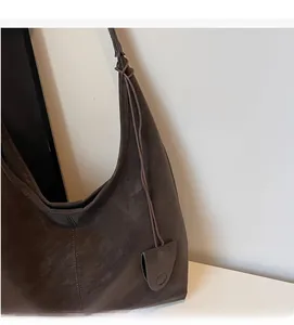 Detail of dark brown vintage tote bag showing matte leather texture and teardrop charm