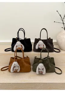 Detail view of four faux suede handbags with plush rabbit charms in various colors