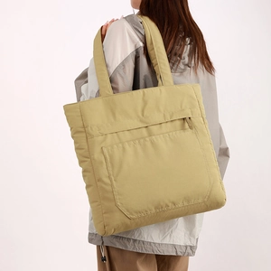 Close-up of khaki quilted tote bag featuring a practical front zipper pocket and soft nylon texture
