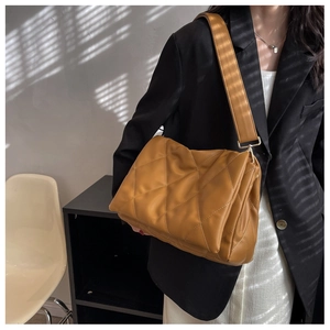 Detail der karamellfarbenen Stepptasche mit breitem Gurt und Rautensteppmuster