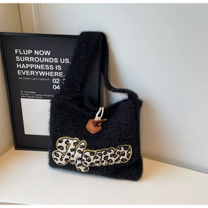 Detail of black knit tote bag showing the leopard print embroidery and horn button closure