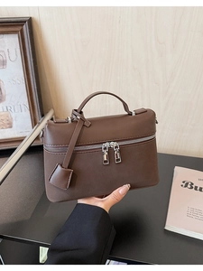 Close-up of deep brown litchi pattern leather handbag with dual zipper closure detail