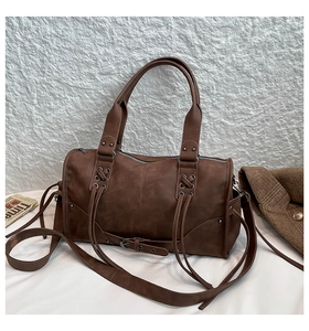 Detailed shot of retro brown leather tote with cross straps and metal rivet accents