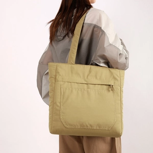 Waterproof khaki tote bag with multiple compartments and a front zipper pocket shown in use