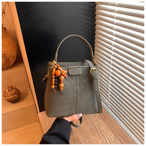 Detail of sage green vintage bucket bag with ethnic wooden beads on wooden table
