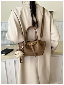 Brown suede crossbody bag with teddy bear charm shown in a cozy lifestyle setting