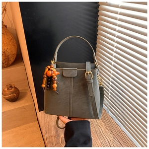 Detail of dark grayish green leather bucket bag with retro wooden bead charm and strap