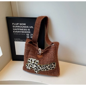 Detail of brown knit tote bag with Mama leopard patch and vintage wooden toggle closure