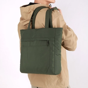 Detailed view of dark green water-resistant nylon tote bag on model's shoulder