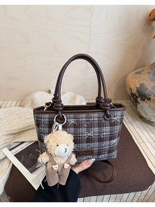 Detail of checkered bucket bag with bow prints and cute plush bear charm accessory