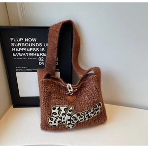 Detail of knitted shoulder bag featuring a leopard print M patch and toggle closure