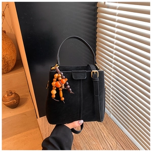 Detail of a black suede bucket bag featuring ethnic style wooden bead charms and handle
