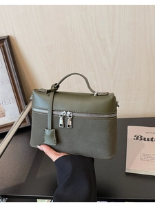 Close-up of olive green matte leather bag with dual silver zippers and top handle details