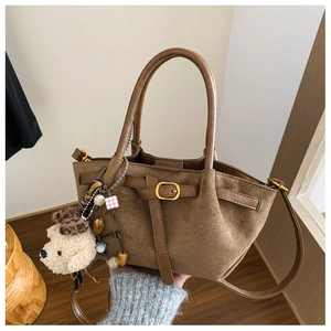 Detail view of brown suede handbag with double handles and a cute plush bear pendant