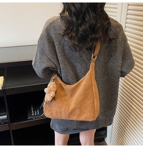 Dettaglio posteriore di una borsa hobo marrone vintage con ciondolo a orsetto su una modella