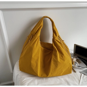 Close-up of yellow oversized nylon hobo bag with pleated texture and metal zipper