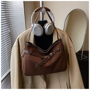 Detailed close-up of brown suede shoulder bag with decorative belt buckle and retro style