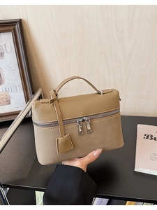 Detail of khaki leather handbag featuring dual zippers and pebbled texture craftsmanship