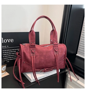 Detail view of burgundy leather tote bag with long tassels and silver rivet accents