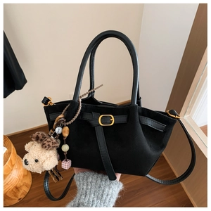 Detail of black suede tote bag with plush bear charm and detachable shoulder strap