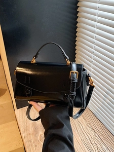 Elegant black glossy leather handbag with vintage gold buckle and adjustable strap