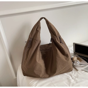 Close-up of brown oversized tote bag showing textured fabric and zipper pockets detail