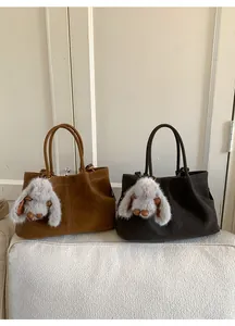 Detail of vintage suede bucket bag in brown with cute plush bunny pendant accessory