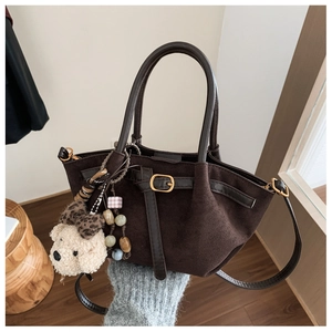 Detailed view of dark brown suede handbag with leather straps and bear charm
