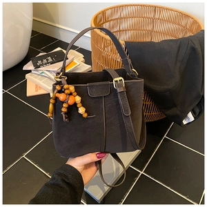 Detail of dark chocolate suede bucket bag with orange and wooden beaded charms