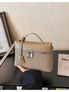 Detail of khaki pebbled leather handbag featuring dual zippers and premium texture