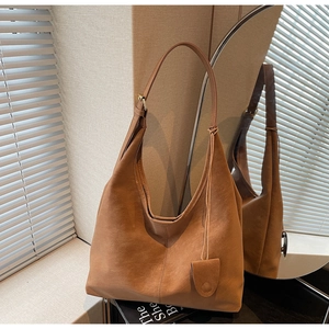 Detail of a brown suede hobo bag with wide shoulder strap in natural light
