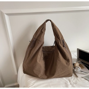 Detail of a large dark brown tote bag with multiple zippers for daily storage