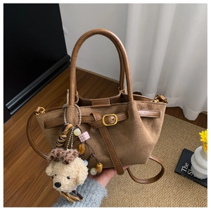 Detailed view of brown suede handbag with leather straps and cute puppy pendant charm