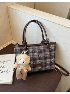 Detailed shot of brown checkered bucket bag with brand logo and cute bear charm accent