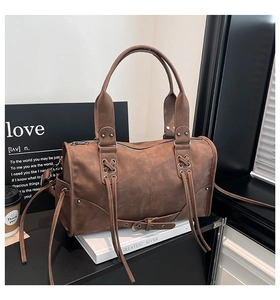 Detail of vintage brown leather handbag featuring metal studs and drawstring accents