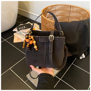 Close-up of vintage bucket bag with litchi texture leather and wooden bead charm