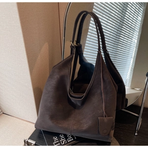 Detail view of a large dark brown tote bag with matte texture in a cozy interior setting
