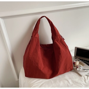 Detail of brick red tote bag with wrinkled nylon texture on white office desk