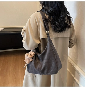 Dettaglio della borsa hobo grigio scuro con ciondolo orsetto marrone sulla spalla