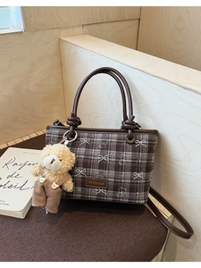 Detail of vintage brown plaid bucket bag with plush bear charm and bow decoration