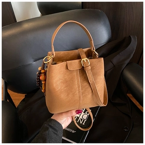 Detail of vintage brown bucket bag with wood bead charm and golden metal buckle accents