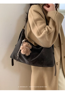 Détail du sac cabas en daim gris avec breloque ours en peluche sur manteau beige