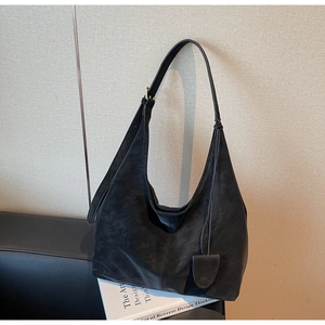 Detail view of large black leather hobo bag with adjustable buckle strap and round charm