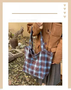 Detail of wool tote bag featuring blue and brown plaid pattern and fine embroidery