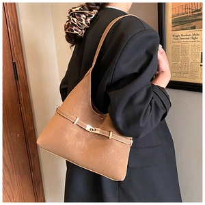 Detail view of brown suede tote bag with a metallic buckle decoration on a shoulder strap