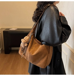 Dettaglio di una borsa tote vintage marrone con un simpatico orsetto di peluche sulla tracolla