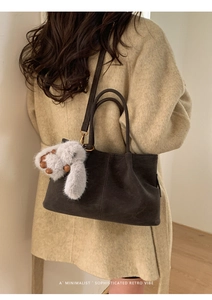 Détail d'un cabas minimaliste en daim marron foncé avec un porte-clés lapin en peluche