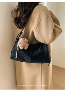 Détail d'un sac cabas en cuir noir minimaliste avec un pendentif d'ours en peluche brun